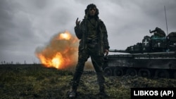 A Ukrainian soldier gestures as a captured Russian tank T-80 fires on a Russian position in the Donetsk region in November 2022.