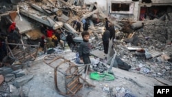 People search the rubble of a building destroyed in an Israeli strike on the Bureij camp for Palestinian refugees in the central Gaza Strip, January 8.